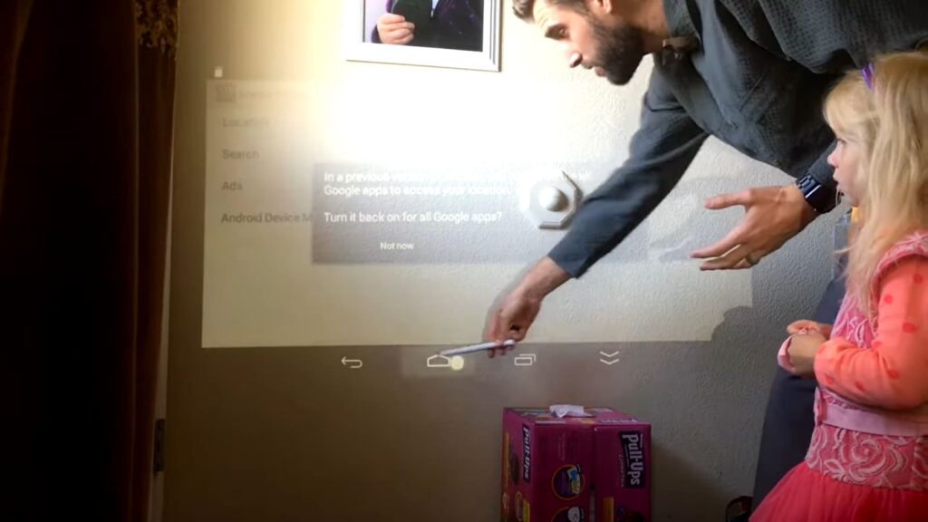 A man and a child interacting with a projector screen menu